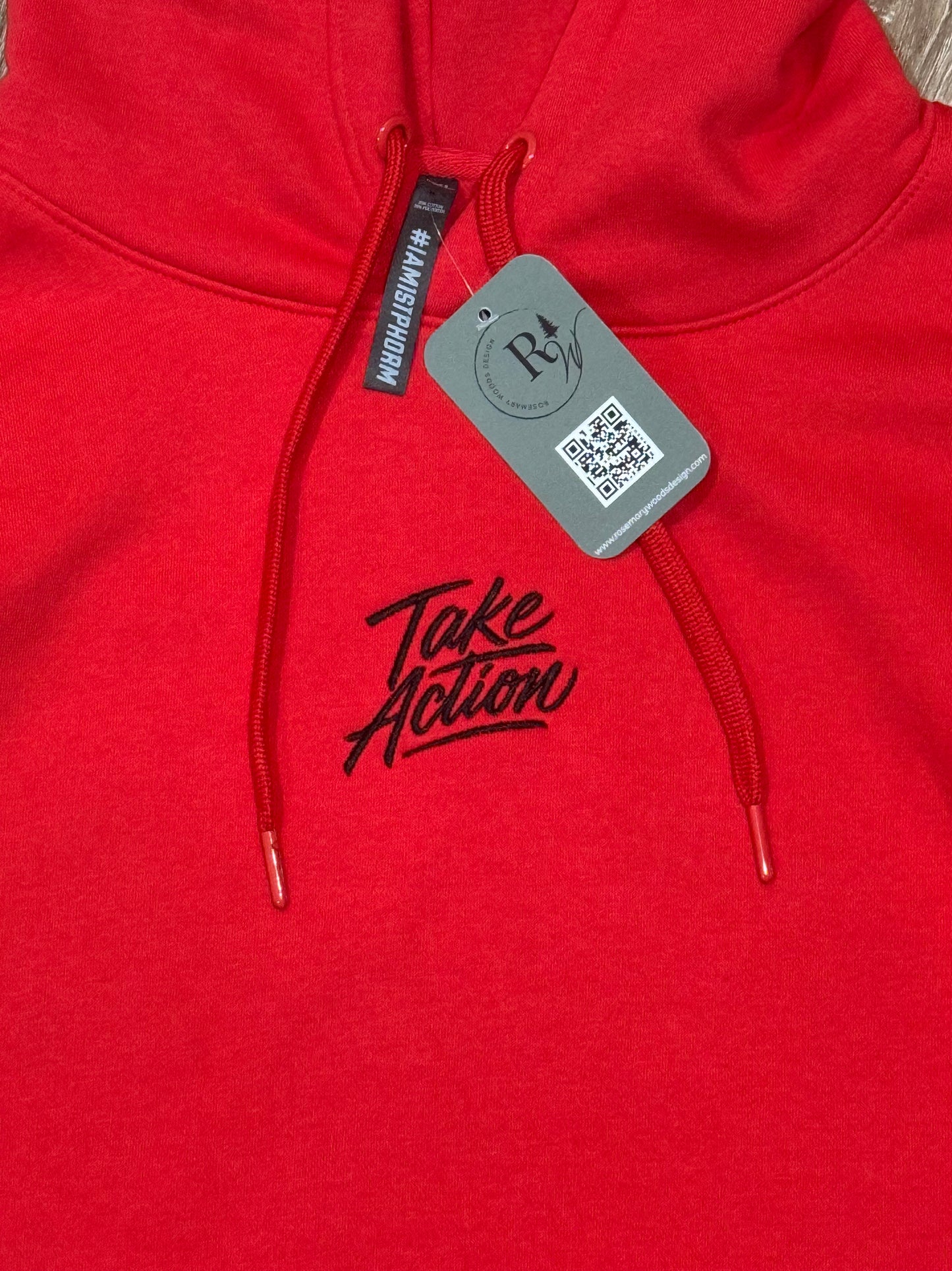 Close up of red hooded sweatshirt with text 'Take Action' embroidered on chest in black