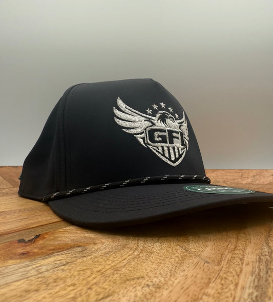Black hat with white GFI eagle logo on a wooden surface side profile