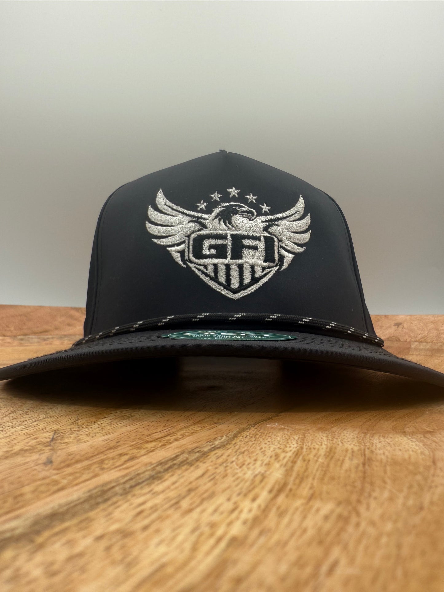 Black and white GFI eagle logo had on a wooden surface front facing