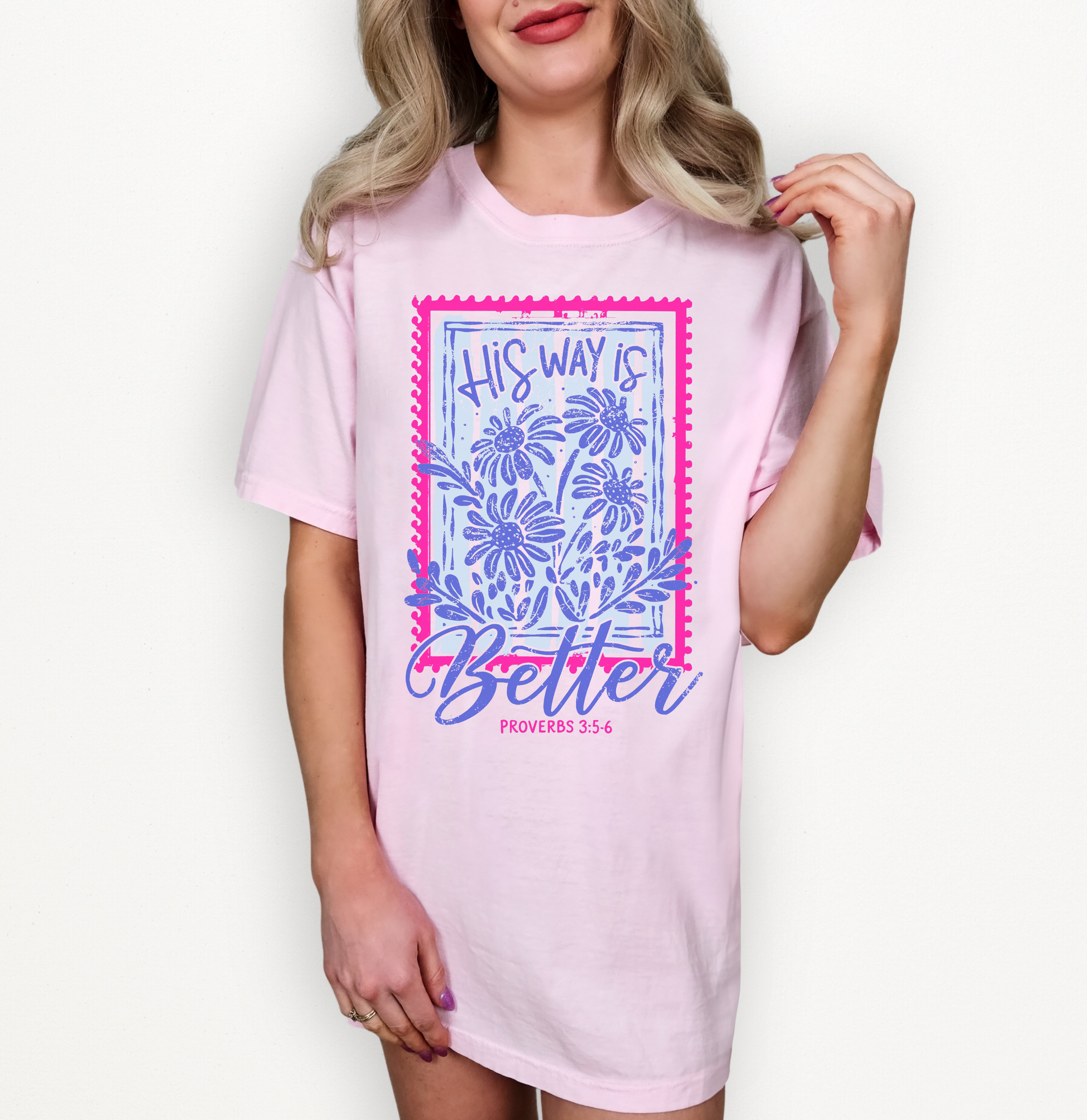 A woman wearing a light pink graphic T-shirt dress with a blue floral design and the text 'THIS WAY IS BETTER' on the front, photographed against a plain white background.