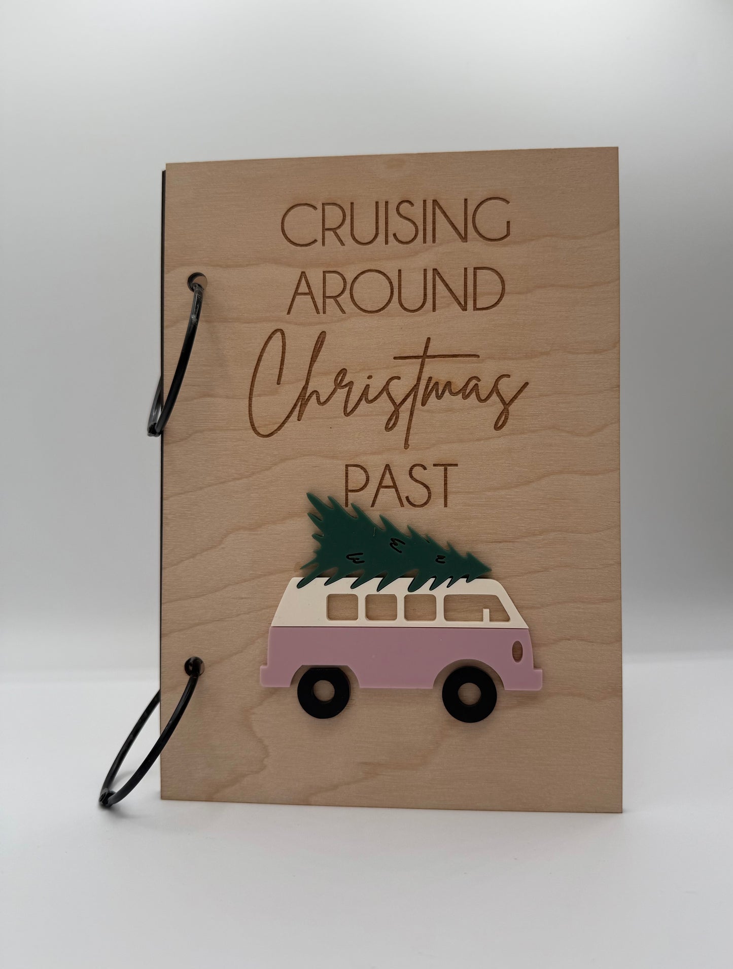  Wooden Christmas greeting card keeper with an acrylic pink retro van carrying a christmas tree design. The words 'Cruising Around Christmas Past' is laser engraved on the top with black binder rings.