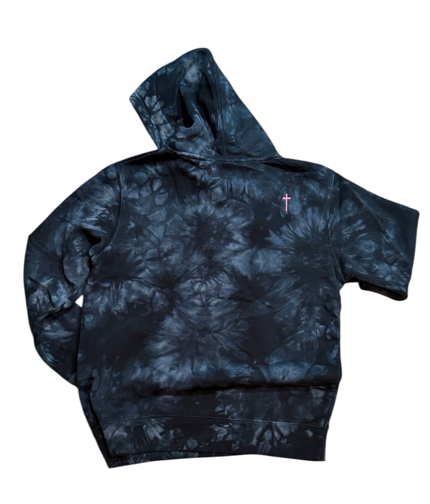 Black and white tie dye hooded sweatshirt a small pink cross embroidered on the back top right on white surface