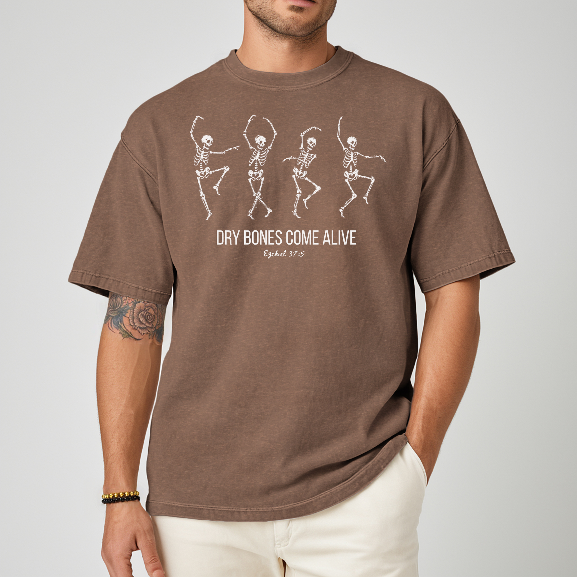 A man wearing a brown graphic t-shirt with white skeleton illustrations and the text 'DRY BONES COME ALIVE' and 'Exodus 20:15'.