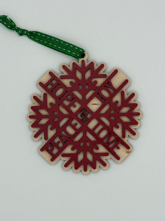 Decorative wooden snowflake ornament that features the words ' Hope, Joy, Love, Peace' in a circular pattern in red. This design features the year in the center.