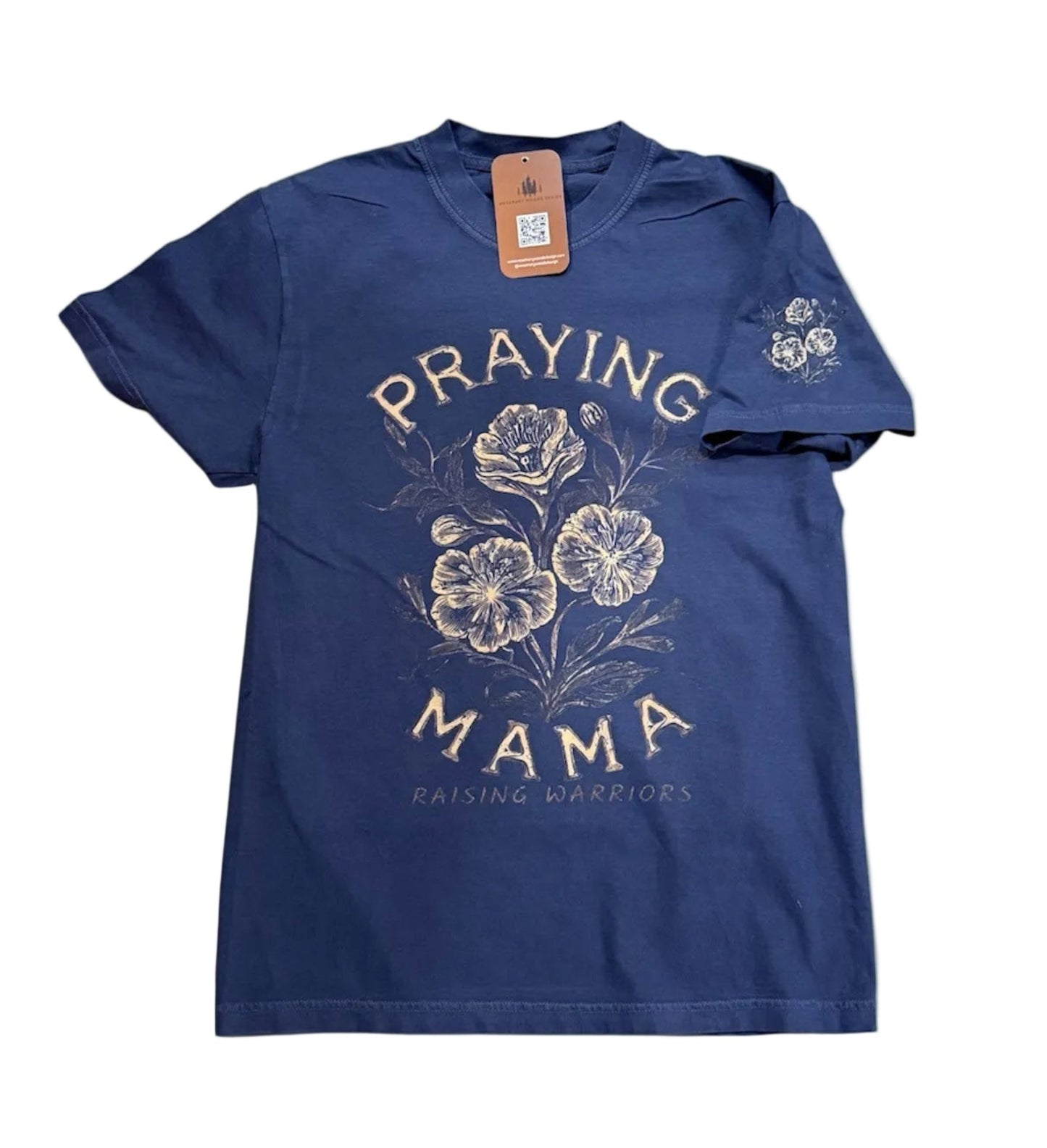 A navy blue short-sleeve t-shirt with a vintage-style graphic on the front featuring the words 'PRAYING MAMA' in cream lettering around a floral illustration. The brand 'RAINS & ROBINS' is printed below the graphic.