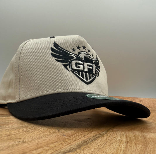 Beige cap with black and white eagle logo on a wooden surface