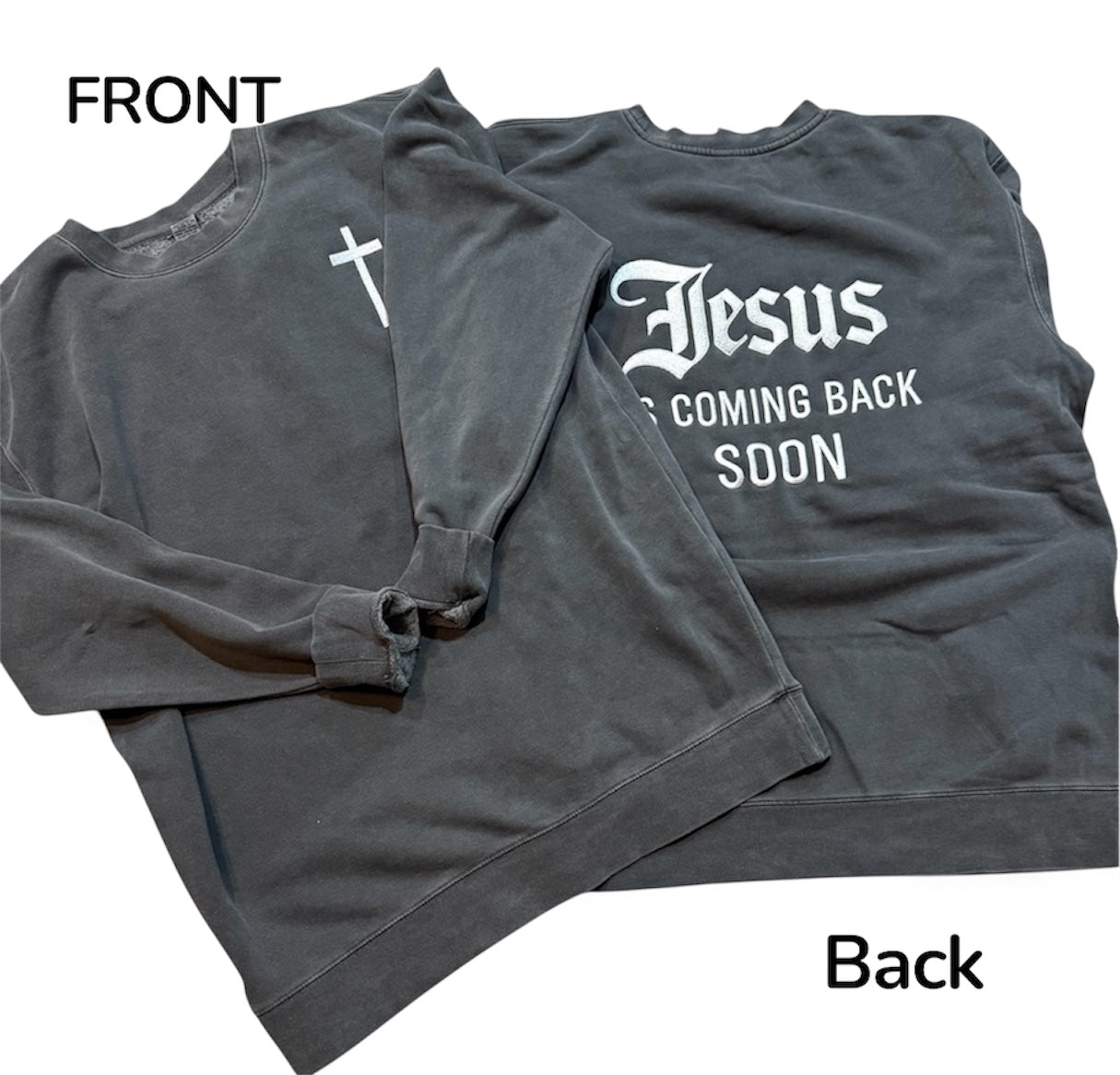 Gray sweatshirt with a cross on the front embroidered and 'Jesus is Coming Back Soon' embroidered on the back, folded on a white background.