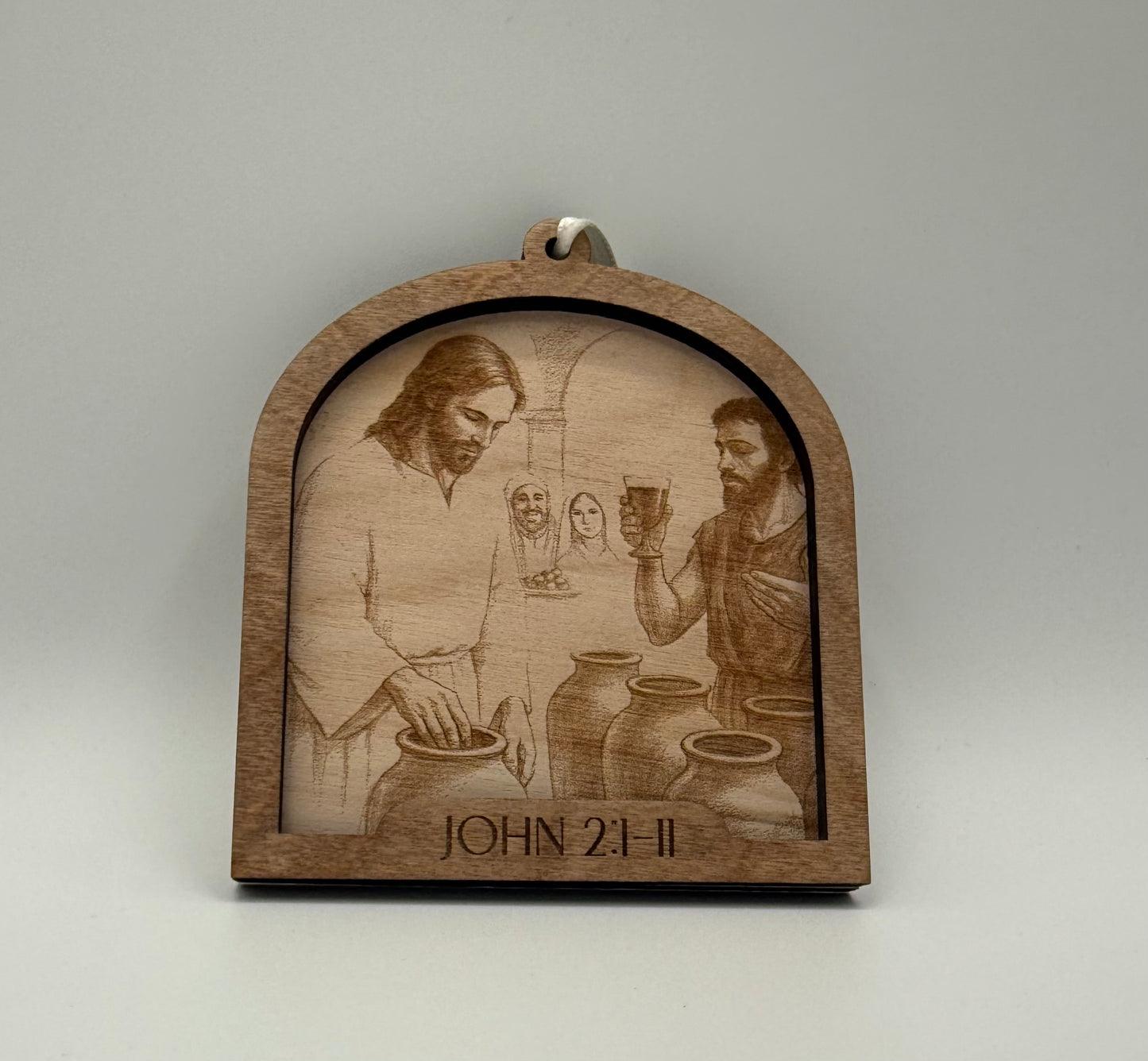 Wooden ornament with a laser engraved scene depicting Jesus turining water into wine. Bible verses John 2:1-11.