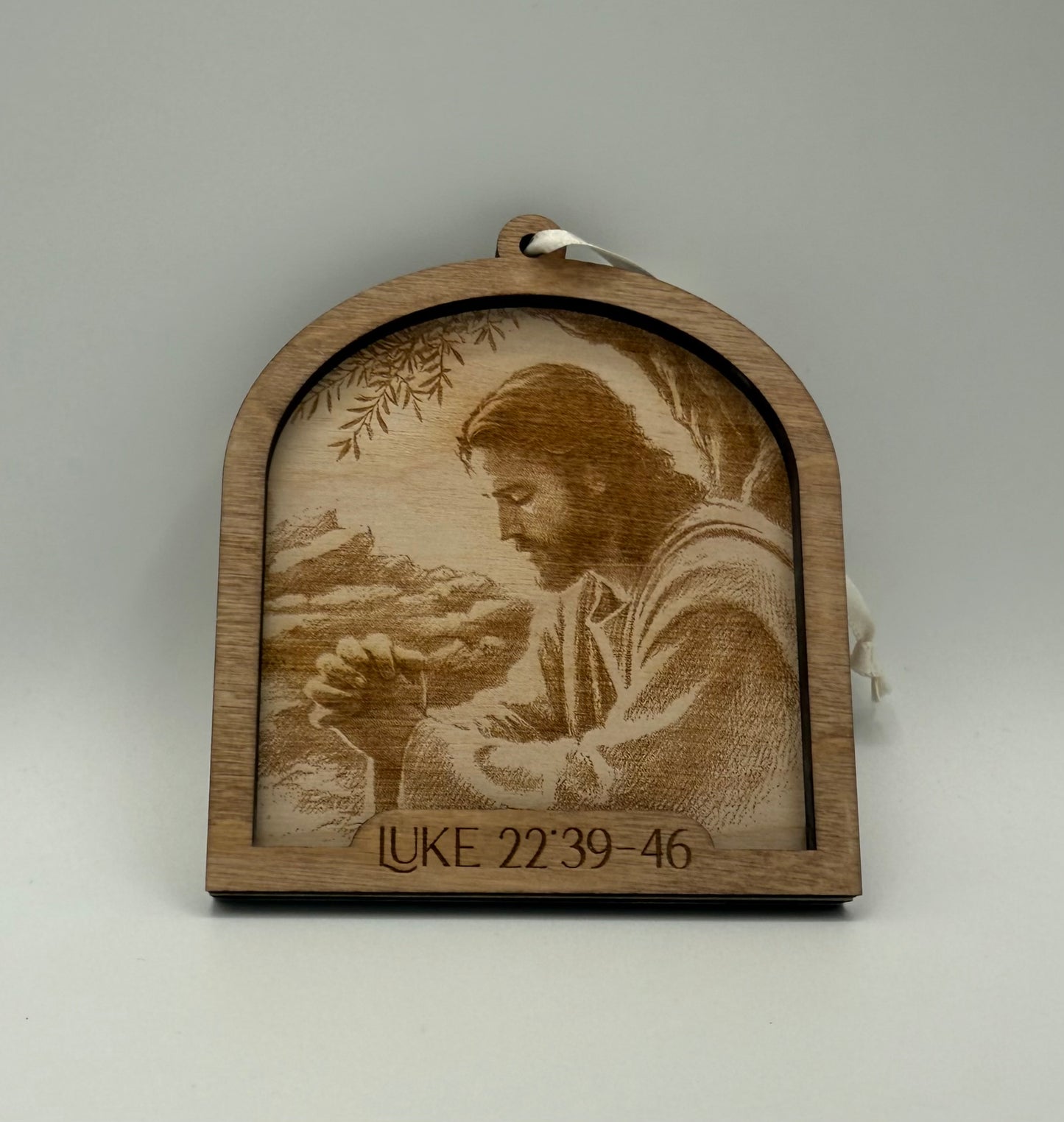 Wooden ornament with a laser engraved scene depicting Jesus praying in the desert. Bible verses Luke 22:39-46.