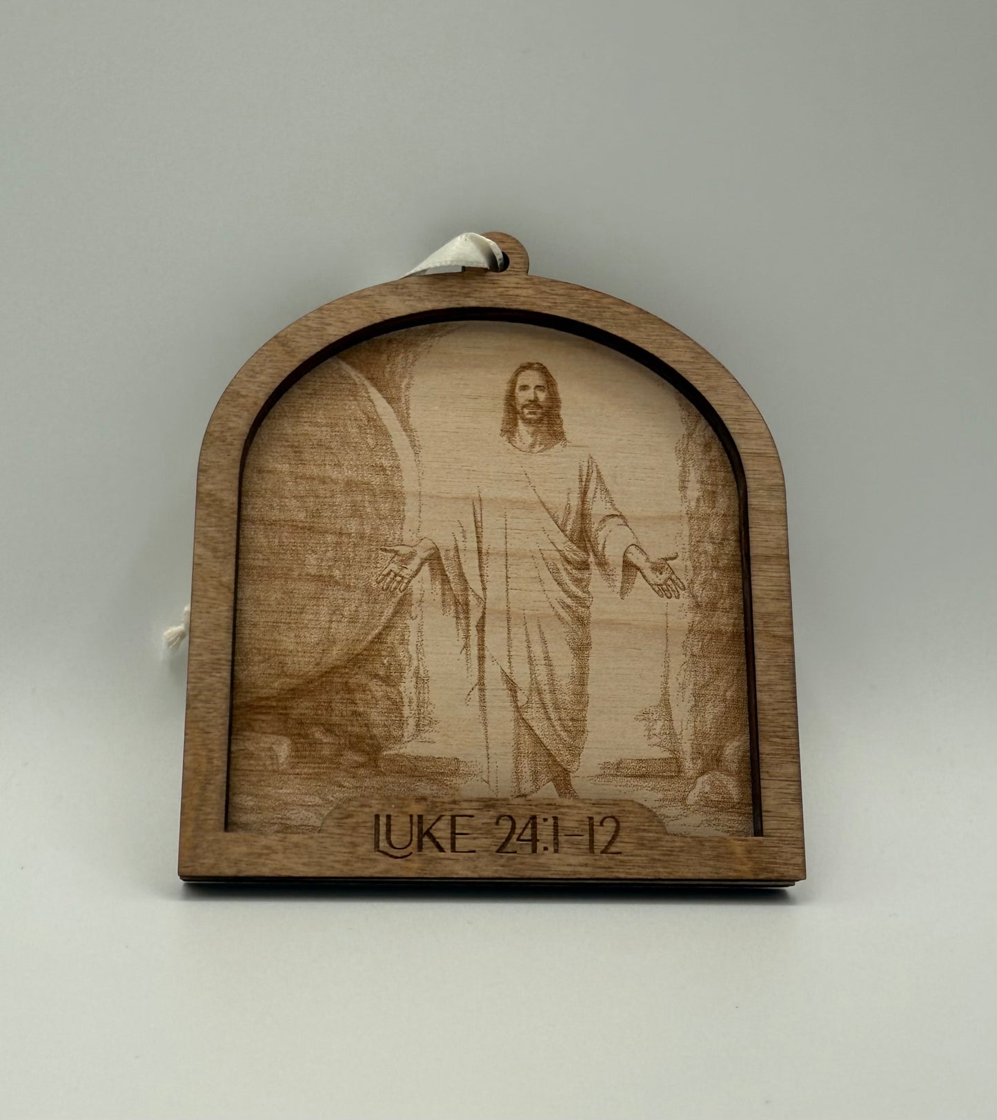 Wooden ornament with a laser engraved scene depicting Jesus in front of the rolled away tomb. Bible verses Luke 24:1-12