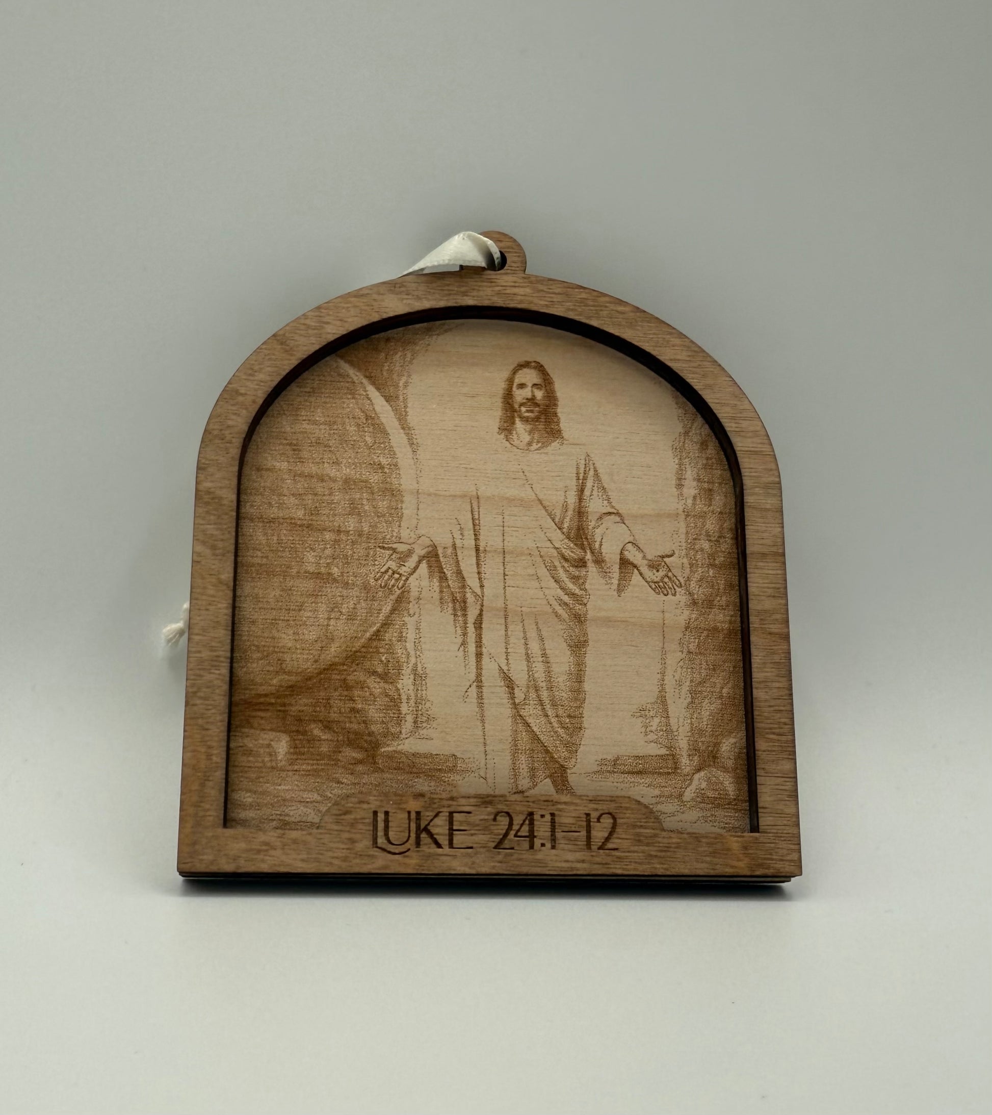 Wooden ornament with a laser engraved scene depicting Jesus in front of the rolled away tomb. Bible verses Luke 24:1-12