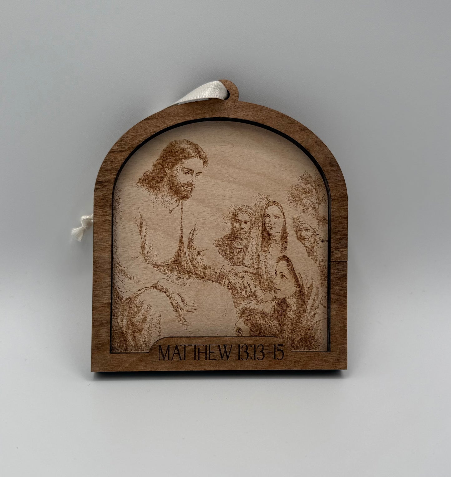 Wooden ornament with a laser engraved scene depicting Jesus praying talking to a young woman. Bible verses Matthew 13:13-15.