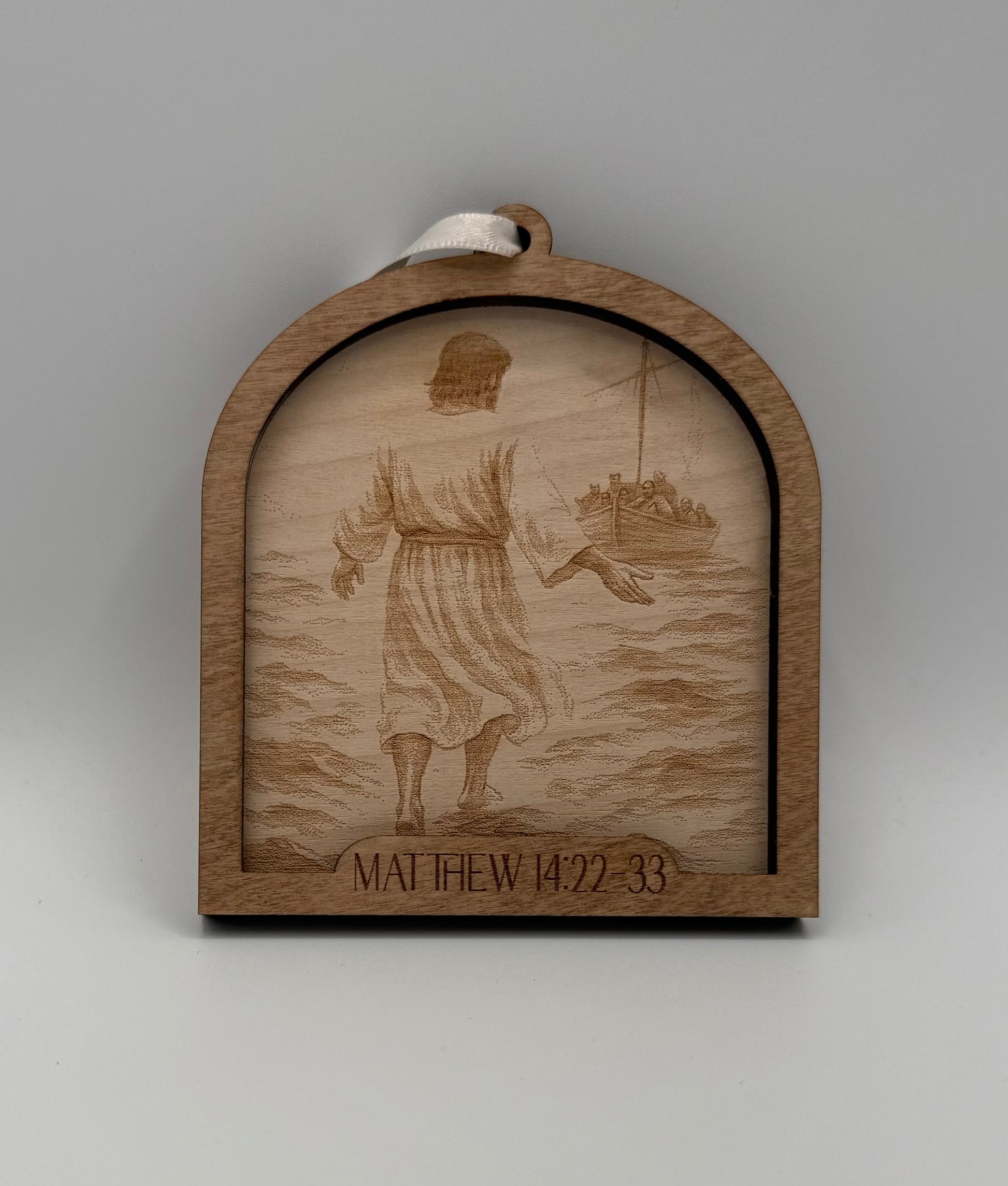 Wooden ornament with a laser engraved scene depicting Jesus walking on the water. Bible verses Matthew 14:22-23.