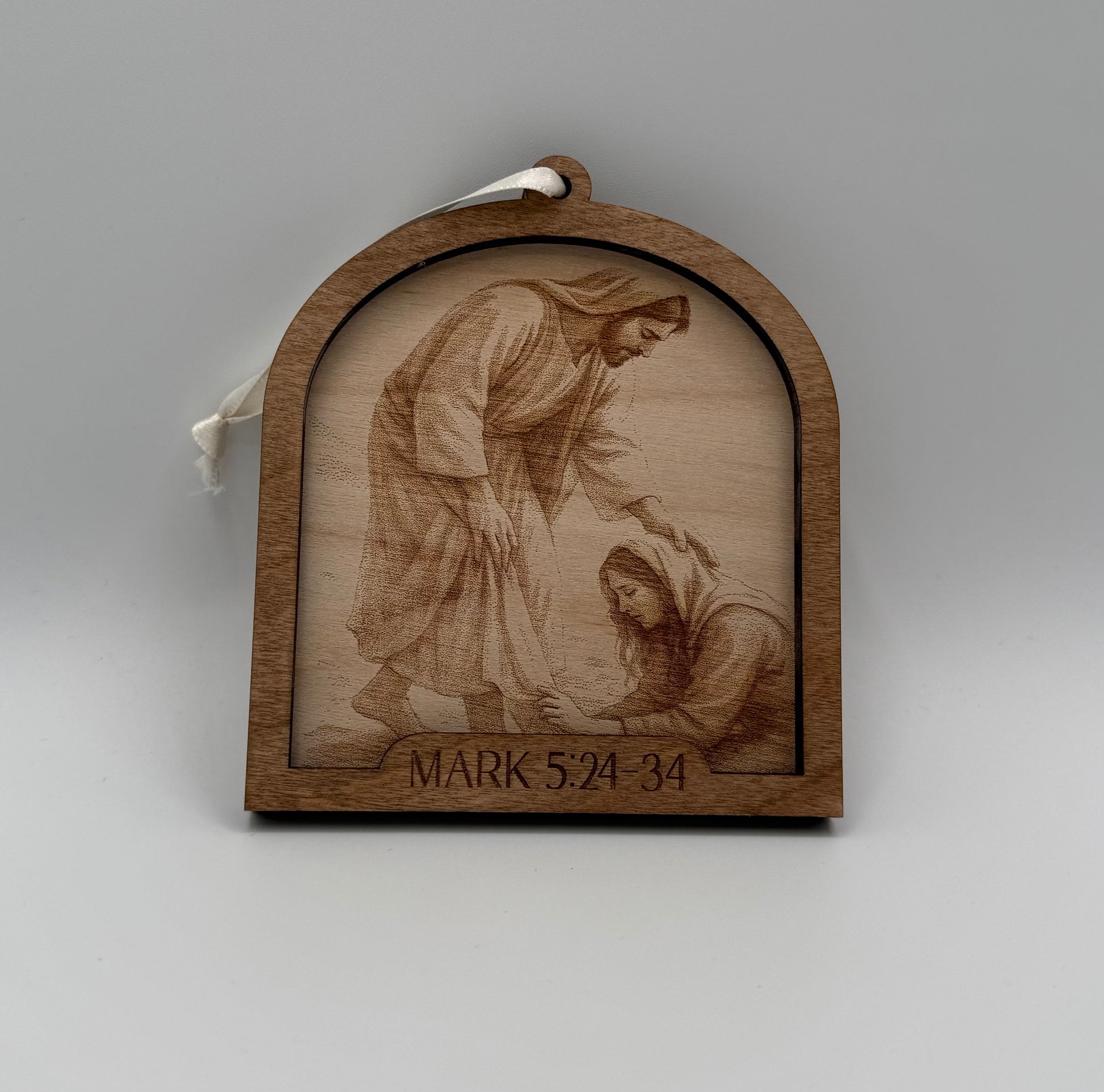 Wooden ornament with a laser engraved scene depicting a woman touching the hem of Jesus. Bible verses Mark 5:24-34.