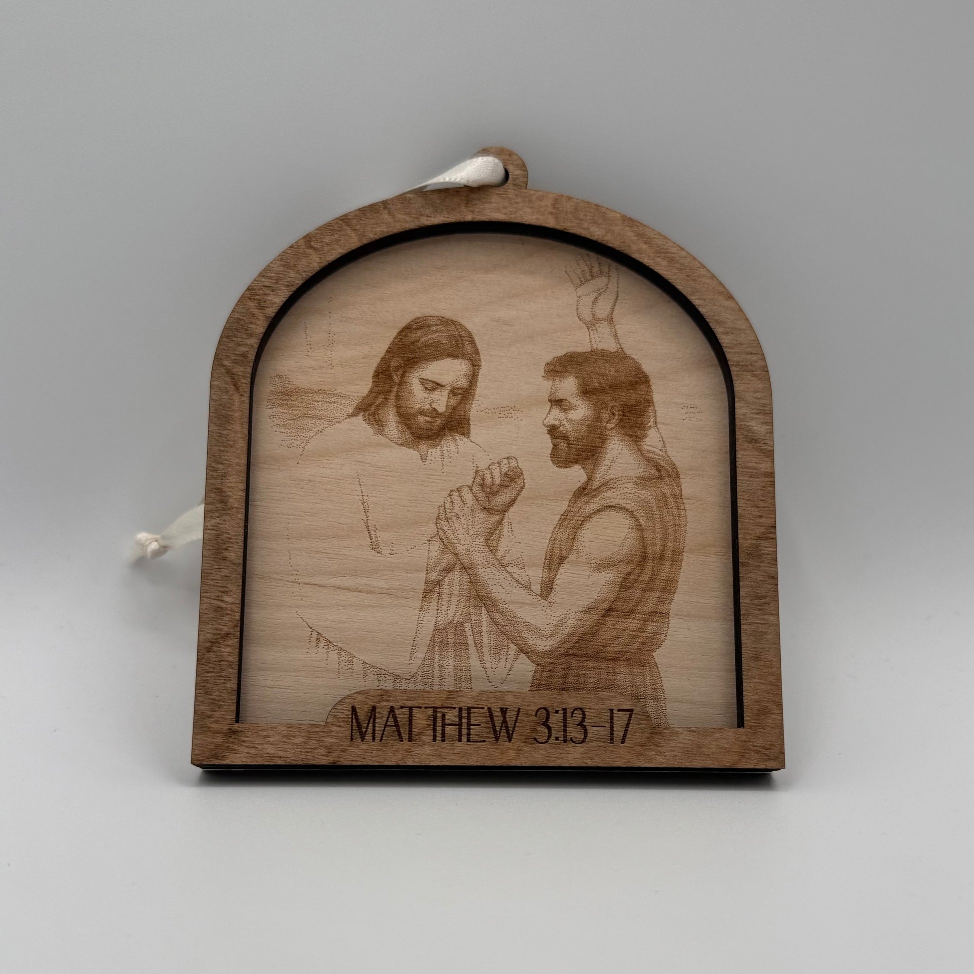 Wooden ornament with a laser engraved scene depicting Jesus praying with man. Bible verses Matthew 3:13-17