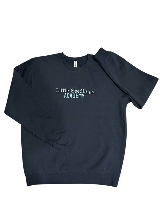 Navy blue sweatshirt with 'Little Seedlings Academy' text embroidered on front center chest in light blue.  This is a zoomed out view with full sweatshirt showing with sleeves folded.