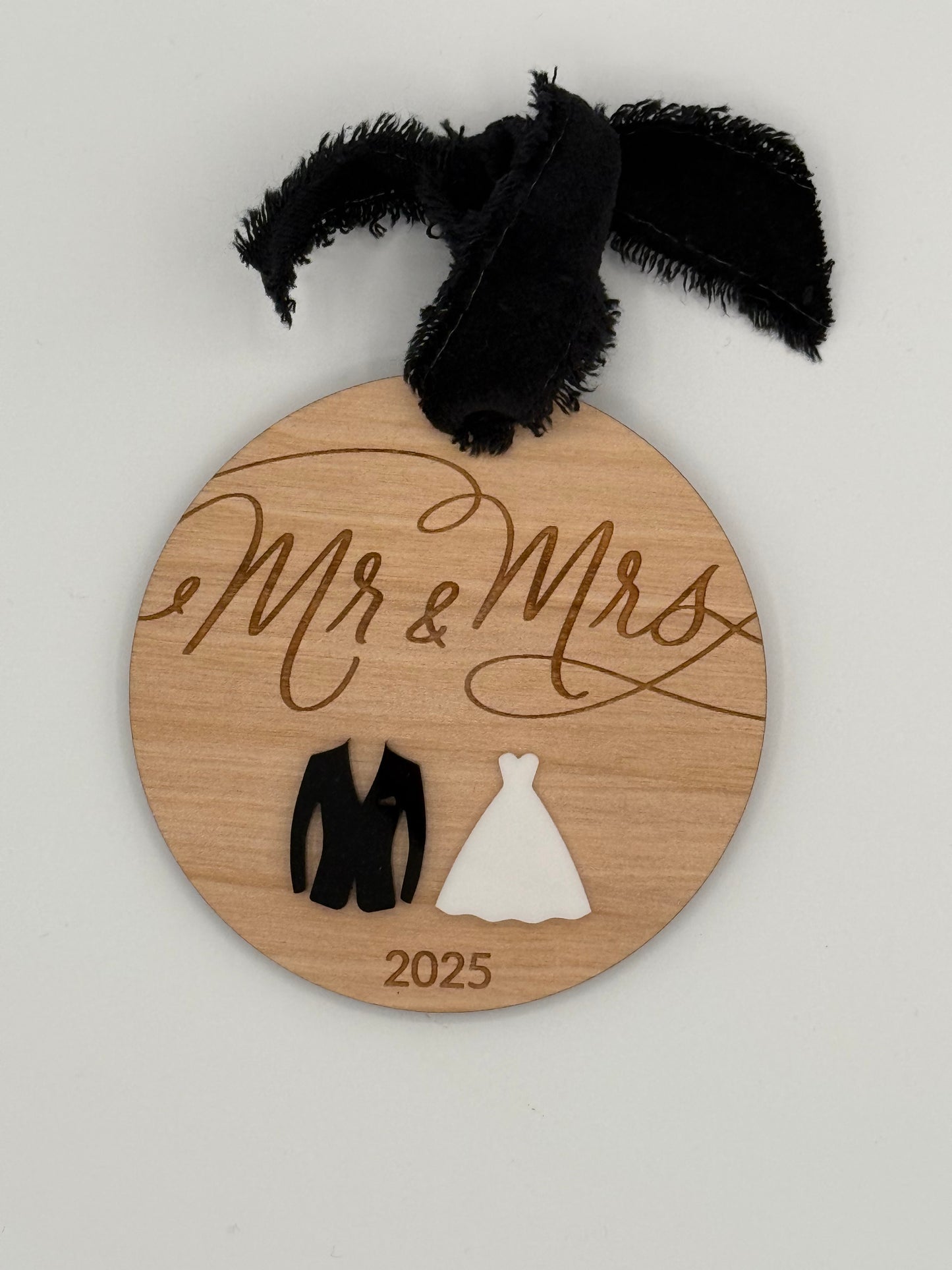 Wooden round ornament with 'Mr & Mrs' and year laser engraved. This design features a black and white acrylic suit and dress that sits underneath the engraved words.