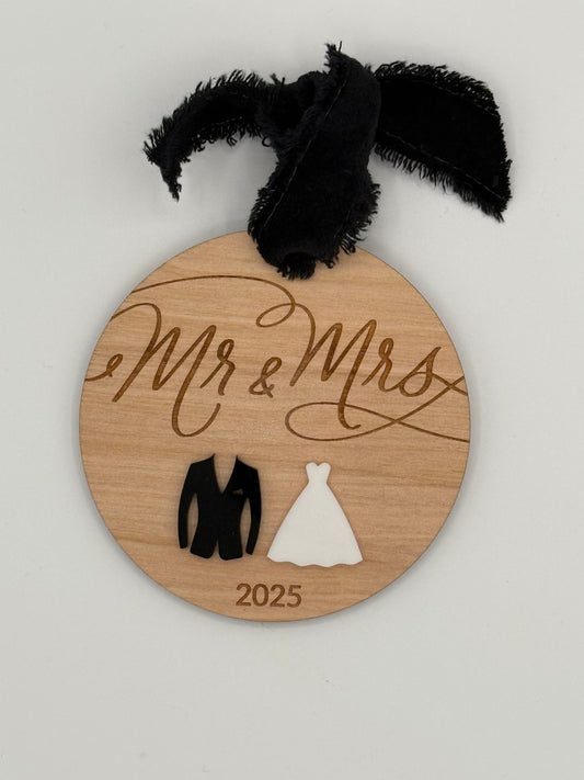 Wooden round ornament with 'Mr & Mrs' and year laser engraved. This design features a black and white acrylic suit and dress that sits underneath the engraved words.