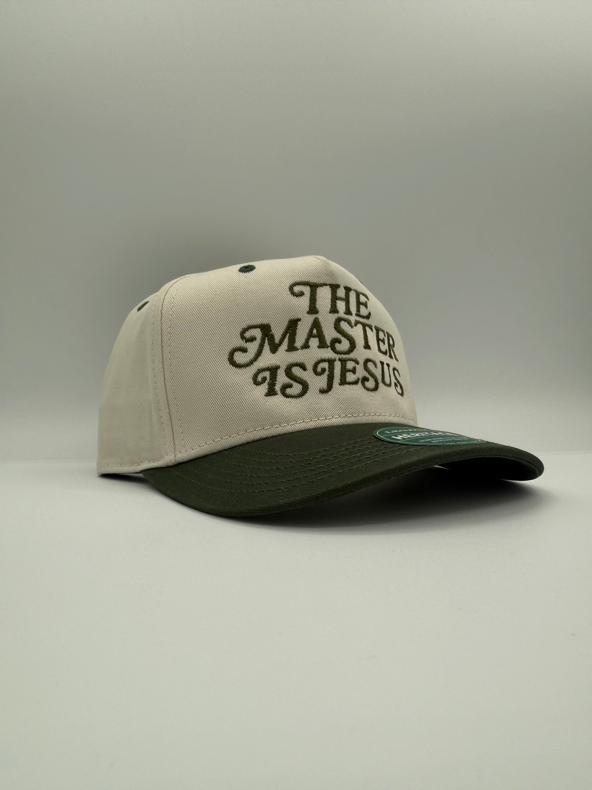 Tan and green two tone hat with the words  'The Master is Jesus' embroidered in green side profile.