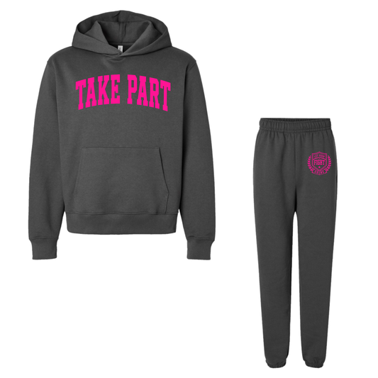 A dark gray two-piece athletic outfit set featuring a pullover hoodie with 'TAKE PART' printed in bright pink across the chest, and matching jogger pants with a small pink crest logo on the upper left thigh.