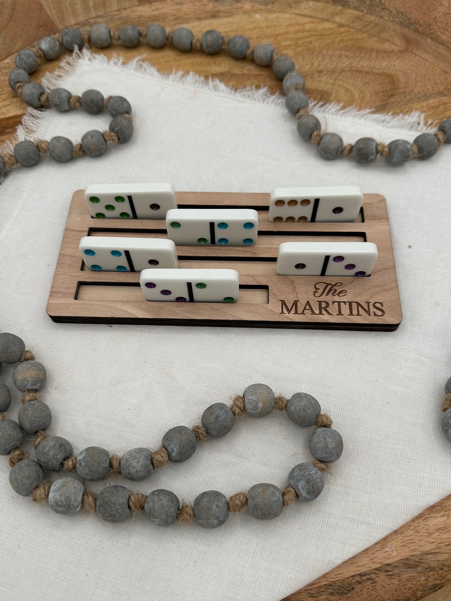 Wooden Mexican train domino holder holding 5 dominos for display with the 'The Martins' laser graved on the front right corner on a light background