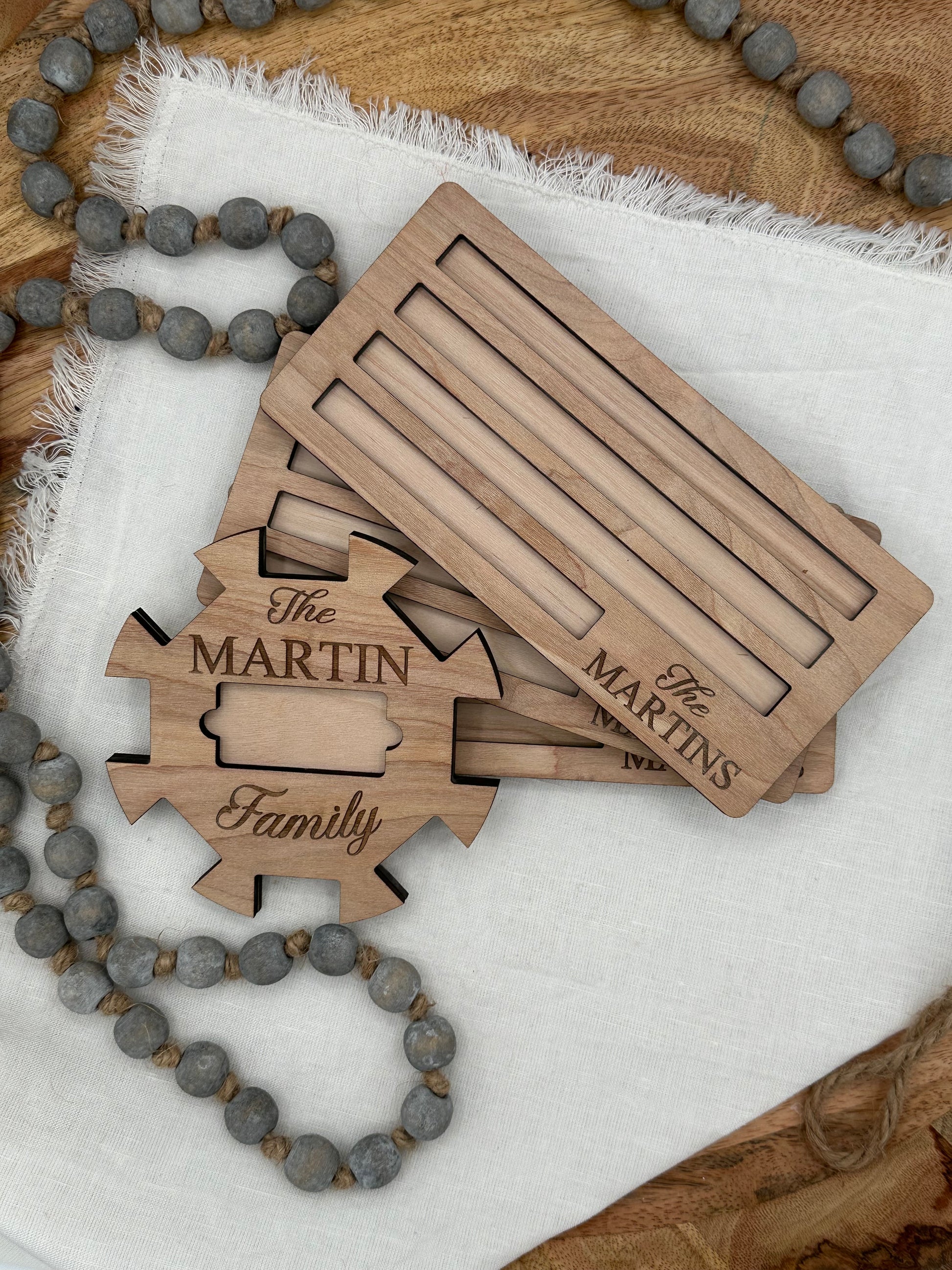 Wooden Mexican train domino center hub with 'The Martin Family' laser engraved on the front and three domino holders with the 'The Martins' laser graved on the front right corner on a light background