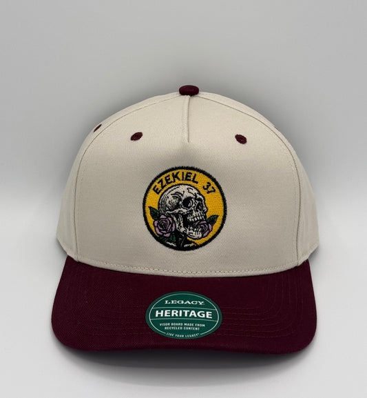 Beige and maroon two toned hat with a skill holding a rose design embroidered in a circle with the words Ezekiel 37
